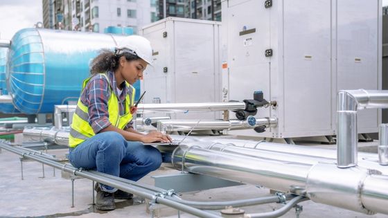 réglementation frigoriste - une femme frigoriste effectuant des vérifications sur un toit avec un ordinateur portable