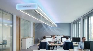 Poutre climatique suspendue au plafond diffusant de l'air dans un bureau moderne avec des employés.