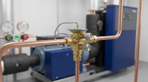 Gros plan sur un détendeur thermostatique MOP en laiton installé sur un réseau de tuyauterie en cuivre.